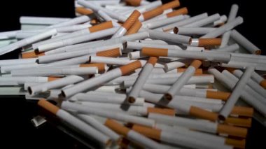 Siyah arka planda dönen ayna masasında bir sürü sigara var.