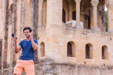 Yakışıklı adamdan gündelik modaya göre Güney Asya kültürü Bollywood dansı. İspanya 'da Asturias unesco anıtı cep telefonuyla mutlu bir şekilde dans ediyor..