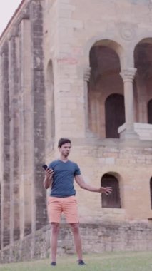 Mutlu Hint etnik köken blogcusu Oviedo İspanya 'daki cep telefonu teknolojisiyle hikayeler kaydediyor. SAnta Maria del Naranco Ortaçağ UNESCO Kilisesi. dikey video, 