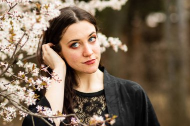 Kendine iyi bak neşeli esmer, dışarıda kameraya bakıyor. Genç bir kadınla doğal güzellik ve doğa bahar çiçeği kavramı.. 