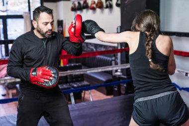 Sağlıklı sporcu azimle çalışıyor. Spor giyim ile dövüş sanatları eğitmenine vurmak. K1 ve kickboks kapalı alanda