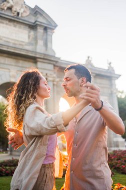 Tutkulu dansçılar güzel bir günbatımında Madrid, İspanya 'daki Puerta de Alcala anıtının önünde Latin dansı yapıyorlar.