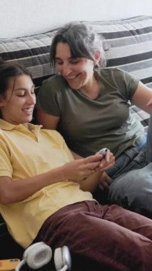 Anne ve kızı evde birlikte kaliteli zaman geçiriyorlar, akıllı telefondan bakıyorlar ve birbirlerine eşlik ederek eğleniyorlar.