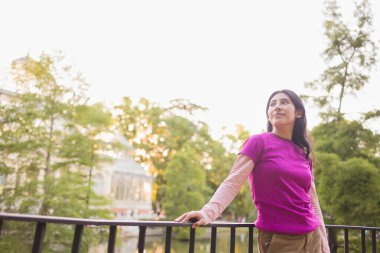 El Etiro Parkı 'ndaki Crystal Palace' da günbatımının tadını çıkaran genç bir kadın, Madrid