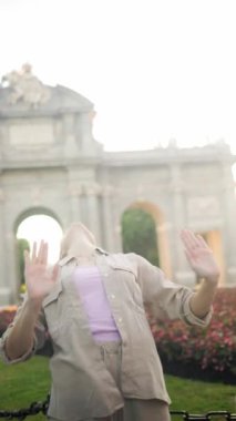 Tourist dancing joyfully in front of the iconic puerta de alcala monument in madrid, spain, showcasing vibrant culture