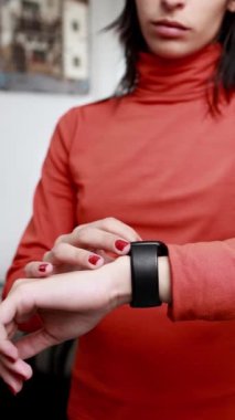 Young woman wearing a smartwatch checks her heart rate while engaging in a workout at home, promoting a healthy lifestyle