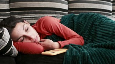 Young woman lying on the couch, deeply sleepy and tired engaged in watching tv or films, showcasing a range of emotions in slow motion