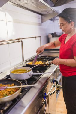 Kadın aşçı, Madrid, İspanya 'da ticari bir mutfakta geleneksel ekvador yemekleri hazırlıyor. Latin Amerika mutfağı sergileniyor.