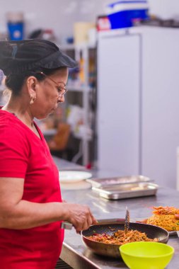 Portoviejo, Manabi, Ekvador 'dan geleneksel bir yemek pişiren kadın aşçı Madrid, İspanya' da ticari bir mutfakta.