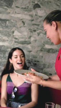 Garson, canlı bir restoran ortamında neşeli bir müşteriye geleneksel bir ekvador yemeği servis ediyor.