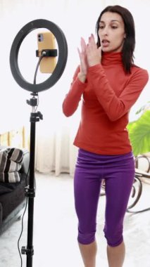 Akıllı telefon önünde dans rutini uygulayan, sosyal medya içeriği için yavaş çekim hareketlerini gösteren bir etken