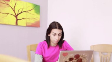 Genç İspanyol kadın evden uzakta çalışıyor, bilgisayarına odaklanmış. Video, girişimciliğin ve modern iş hayatının dengesinin özünü yakalıyor.