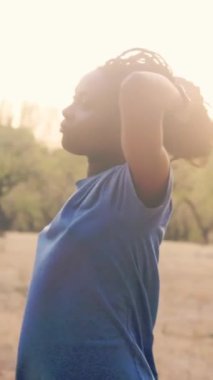 Genç siyah Ekvator 'lu kadın spor giyer, parkta egzersiz yaptıktan sonra rahatlar ve doğanın tadını çıkarır.