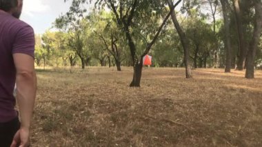 Olgun bir beyaz adam oryantasyon yarışına katılıyor, ağaçların arasında geziniyor ve bir kontrol noktası kuruyor.