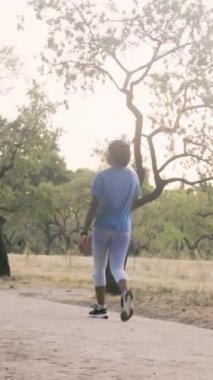 Genç bir kadın sağlıklı bir yaşam tarzından hoşlanıyor. Parkta yürürken akıllı sesiyle müzik dinliyor.