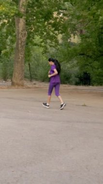 Mor spor giyimli kararlı Latin sporcu yaz günü yeşil parkta koşuyor. Formda ve sağlıklı olduğunu gösteriyor.