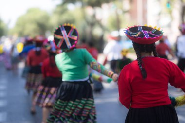 Renkli geleneksel Andean kıyafetleri giyen kadınlar İspanyol kökenlerini kutlayan bir geçit törenine katılıyorlar.