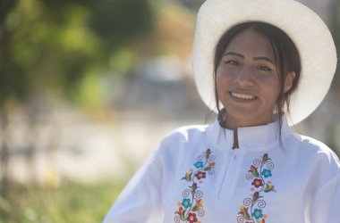 İspanyol kökenli kadın geleneksel beyaz elbise ve şapka giyip İspanyol mirası kutlamalarında gülümsüyor.