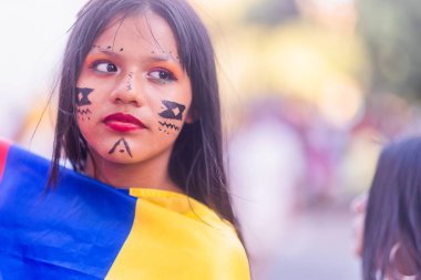 Geleneksel yüz boyalı genç kız Kolombiya bayrağına sarılmış ulusal bayramı kutluyor.