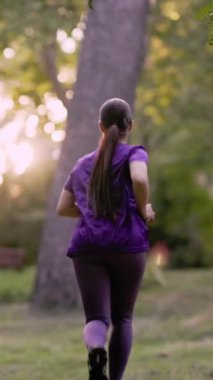 Mor spor giyimli Latin atlet, altın saat boyunca güneş parkında enerjik bir şekilde koşuyor, sağlıklı yaşam ve aktif yaşam tarzını somutlaştırıyor.