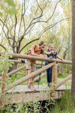 Üst düzey bir çift, Madrid, İspanya 'da tahta bir köprüde dikilirken doğayı gezmekten, keşfetmekten ve ilginç bir şeye işaret etmekten zevk alıyor.