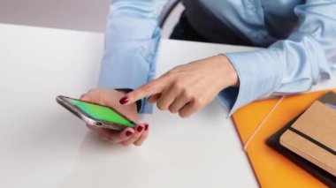 Beyaz arka planda izole edilmiş yeşil ekranlı akıllı telefonla konuşan Latin bir iş kadınının yavaş çekimini kapat.