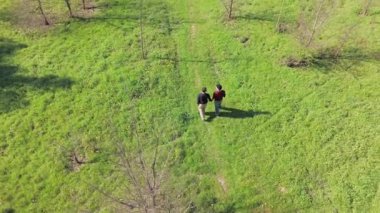 Havadan birlikte yürüyen eşcinsel çifti görüntülemek, yeşil park manzarası arasında samimi sohbetler etmek, bağlantı kurmak ve birlikte olmak.