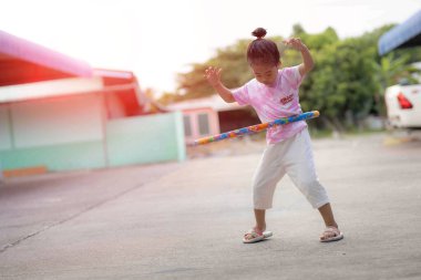 Bir kız kiralık bir evde hulahop oynayarak eğleniyor. Mutlu bir şekilde gülümsüyor.
