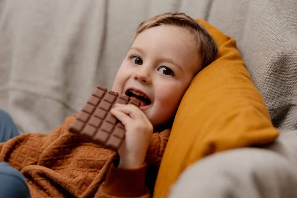 Niño Adorable Sentado Sofá Casa Comiendo Chocolate Niño Dulces Confitería — Foto de Stock