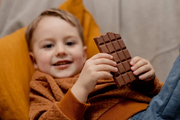 Niño Adorable Sentado Sofá Casa Comiendo Chocolate Niño Dulces Confitería — Foto de Stock