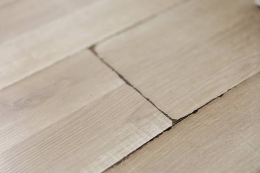 Şişmiş ve kirli kaplama zemin, yakın görüş. Nem hasarı. Laminate döşemesi şişti. Hasarlı kaplama tahtaları. Ev, emlak sigortası
