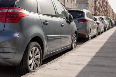 Şehir caddesi boyunca park etmiş çeşitli arabaların olduğu sıra şehir otoparkındaki tipik manzarayı gösteriyor. Kentsel planlama makaleleri, park yönetimi içeriği, ulaşım teması çizimleri için ideal