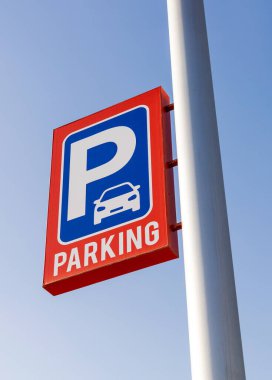 Açık gökyüzüne karşı kırmızı ve mavi park işareti, beyaz direğe monte edilmiş. Kentsel planlama, ulaşım, altyapı ve kamu park tesisleri için mükemmel bir kullanım alanı. Otopark fiyatı
