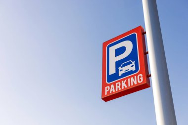 Açık gökyüzüne karşı kırmızı ve mavi park işareti, mesaj için boşluk kopyala. Kentsel planlama, ulaşım, altyapı ve kamu park tesisleri için mükemmel bir kullanım alanı. Otopark fiyatı