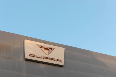 Torrevieja, İspanya - 09-07-2024: Cupra logosu, açık mavi gökyüzü altında, otomotiv markalaşması ve bayilik tasarım unsurlarını sergilemek için mükemmel olan modern bir binanın ön cephesinde belirgin bir şekilde sergilendi