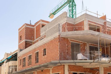 Açık gökyüzünün altında tamamlanmamış tuğla ve beton bina olan bir inşaat sahasına yakın çekim. Kentsel gelişim, mimari ve inşaat ile ilgili içerik için mükemmel