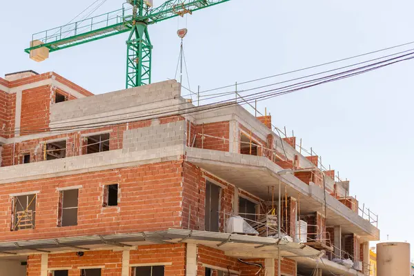 stock image Vivid capture of construction site showcasing building in progress with brickwork and crane lifting materials. Ideal for real estate, development projects, and construction industry themes