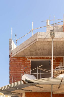 Açık gökyüzünün altında tamamlanmamış tuğla ve beton bina olan bir inşaat sahasına yakın çekim. Kentsel gelişim, mimari ve inşaat ile ilgili içerik için mükemmel