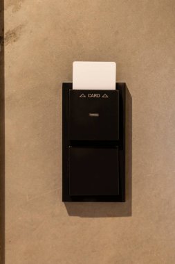 Kart okuyucu düz, açık renkli bir duvara monte edilir ve misafirlerin giriş kartlarını okutarak bir otel odasına girmelerine olanak sağlar. Minimalist tasarım atmosferi geliştirir.