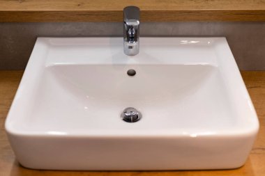 Şık bir banyo lavabosu pürüzsüz, dikdörtgen bir tasarıma sahiptir. Cilalı bir muslukla tamamlanır. Lavabo doğal ahşap bir tezgaha kurulmuş, çağdaş bir görünüm ve basit bir zarafet yaratıyor..
