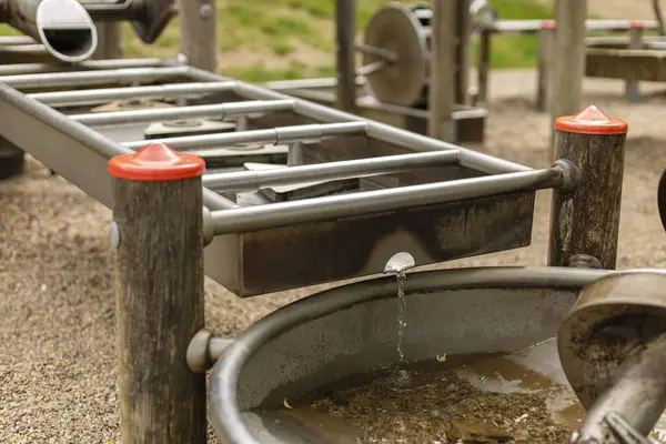 Bir oyun parkındaki su oyun istasyonu çocukları su akışını keşfetmeye ve onunla meşgul olmaya davet eder. Çocuklar etkileşimli özellikler ve elementlerle oynarken suyun hareketini gözlemleyebilirler..