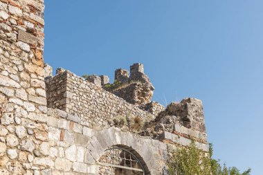 Antik şato, etkileyici taş duvarlar ve parlak mavi gökyüzüne karşı siperler sergiliyor. Yeşillik harabeleri süslüyor, bu sitenin tarihsel önemini vurguluyor..