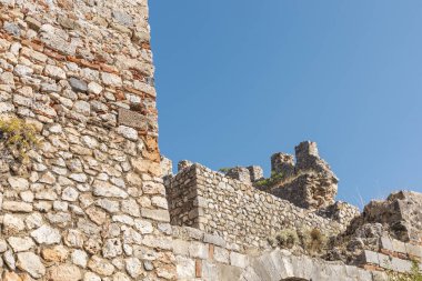 Yıpranmış bir taş kale, canlı mavi bir gökyüzünün altında sergilenen taşları harap eder. Kalıntılar, bu manzaralı yerde bir tarih ve keşif hissi uyandırıyor..