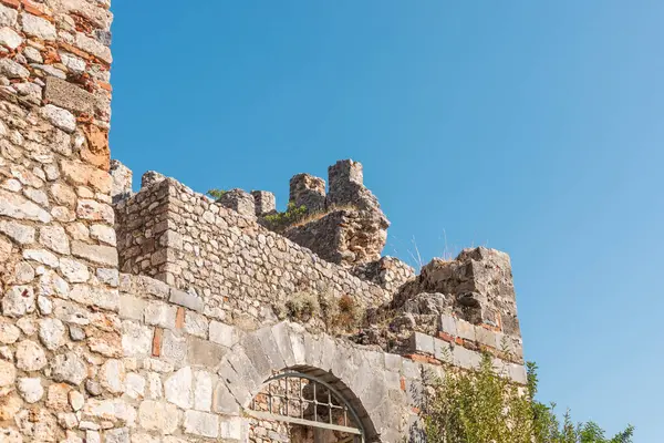 Antik şato, etkileyici taş duvarlar ve parlak mavi gökyüzüne karşı siperler sergiliyor. Yeşillik harabeleri süslüyor, bu sitenin tarihsel önemini vurguluyor..