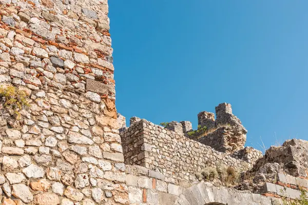 Yıpranmış bir taş kale, canlı mavi bir gökyüzünün altında sergilenen taşları harap eder. Kalıntılar, bu manzaralı yerde bir tarih ve keşif hissi uyandırıyor..