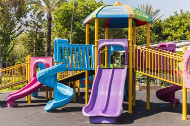 Canlı bir oyun parkında çoklu renkli slaytlar ve çocuklar için güneşli bir parkta oynamak için tasarlanmış tırmanma alanları vardır..