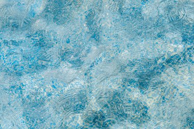 Parlak mavi su, güneş ışığı altında parlar ve el değmemiş bir yüzme havuzunda pırıl pırıl bir etki yaratır. Yüzey hafifçe dalgalanır. Rahatlamak ve eğlenmek için mükemmel bir gün olduğunu gösterir..