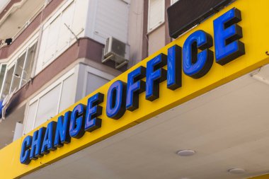 Değişim Ofisi yazan canlı sarı bir tabela kentsel bir bölgede dikkat çekiyor..