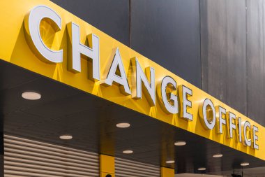 Parlak renkli bir ofis tabelası modern bir şehir zeminine karşı çıkıyor. Harfler açık ve kalın. Gündüz işlem hizmetlerini gösteriyor..