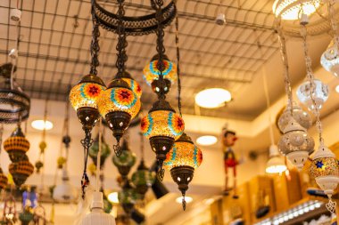 Hareketli bir pazarda tavandan canlı fenerler sarkıyor. Alışverişçiler gün batımından önceki karmaşık tasarımlara hayranlık duyarken uzay boyunca renkli desenler sergiliyorlar..